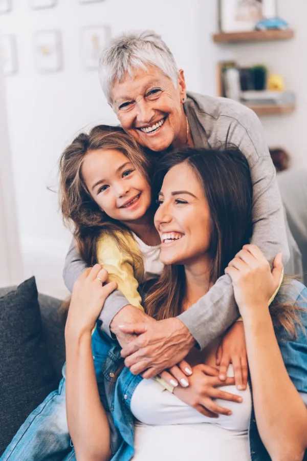 Grandmother hugging her daughter and granddaughter during a visit in a brightly lit visiting area
