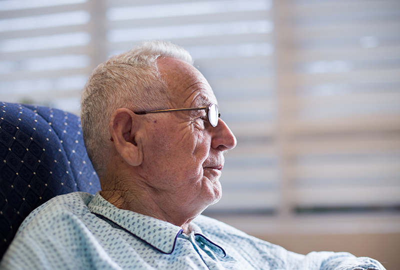 Elderly man in pajamas sitting in comfort watching television