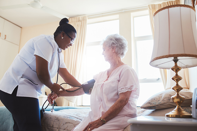 Female nurse checking the blood pressure of an elderly woman in a care facility.